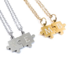 Set van twee puzzelstuk kettingen in zilver en goud stainless steel, close-up van de puzzel hangers.